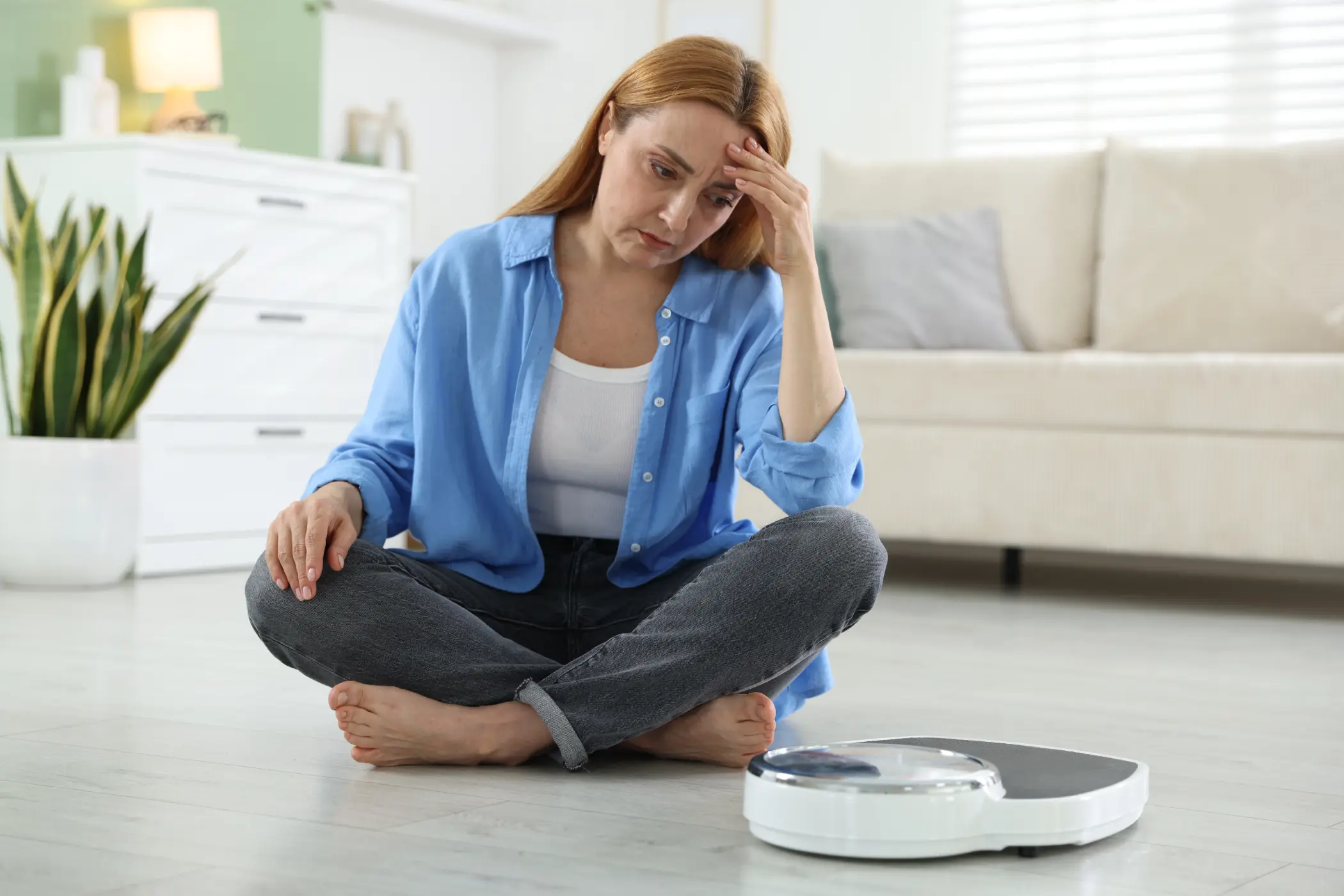 woman upset sitting by scale and wants to know how to prevent menopause weight gain